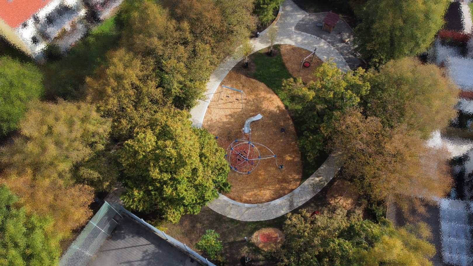 Luftaufnahme eines kreisförmigen Parks mit herbstlichen Bäumen und buntem Boden.